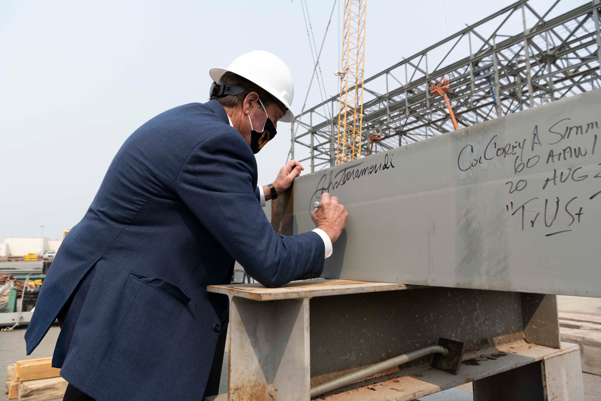 A man signs his name on a steel beam