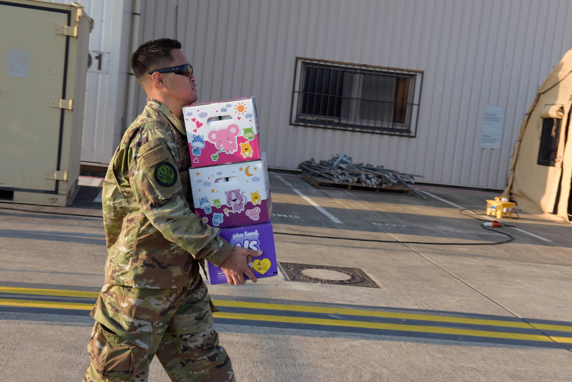An aiman walks with a handful of boxes.