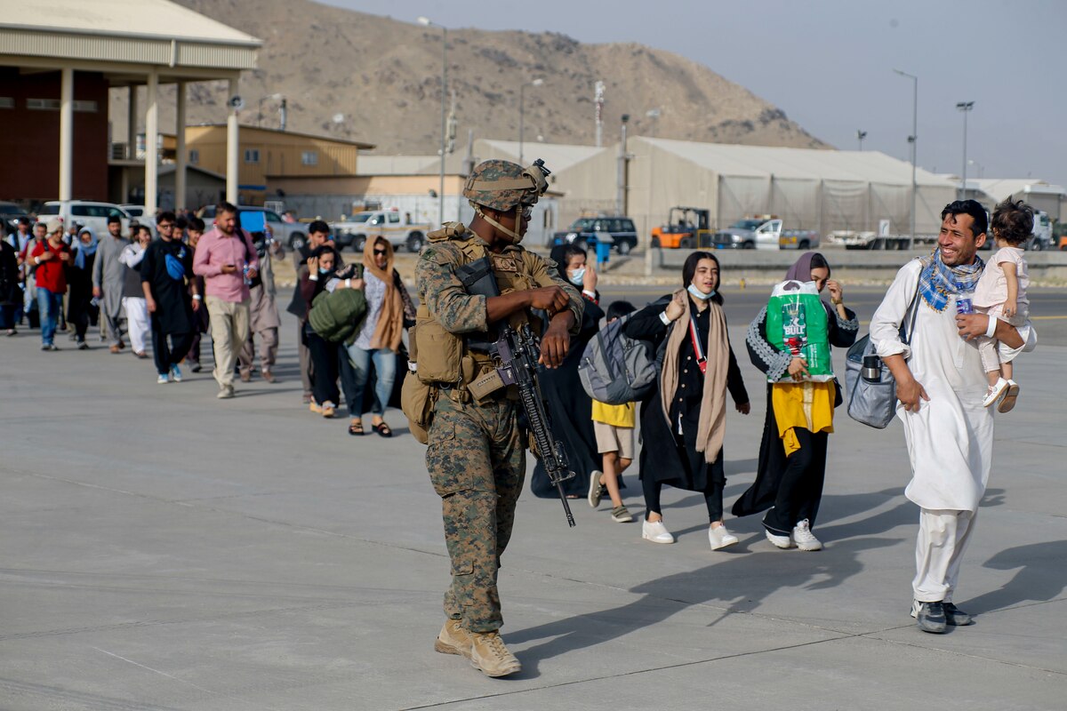 A Marine walks alongside a line of people.