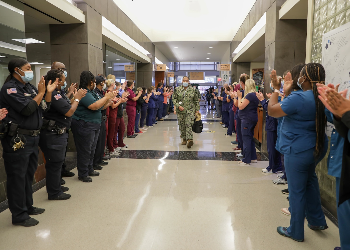 Ochsner Lafayette General Medical Center staff welcome a medical support team from Navy Medicine Readiness and Training Command Bethesda as they enter the hospital to begin their in-processing during COVID-19 response operations in Lafayette, Louisiana, Aug. 18, 2021.