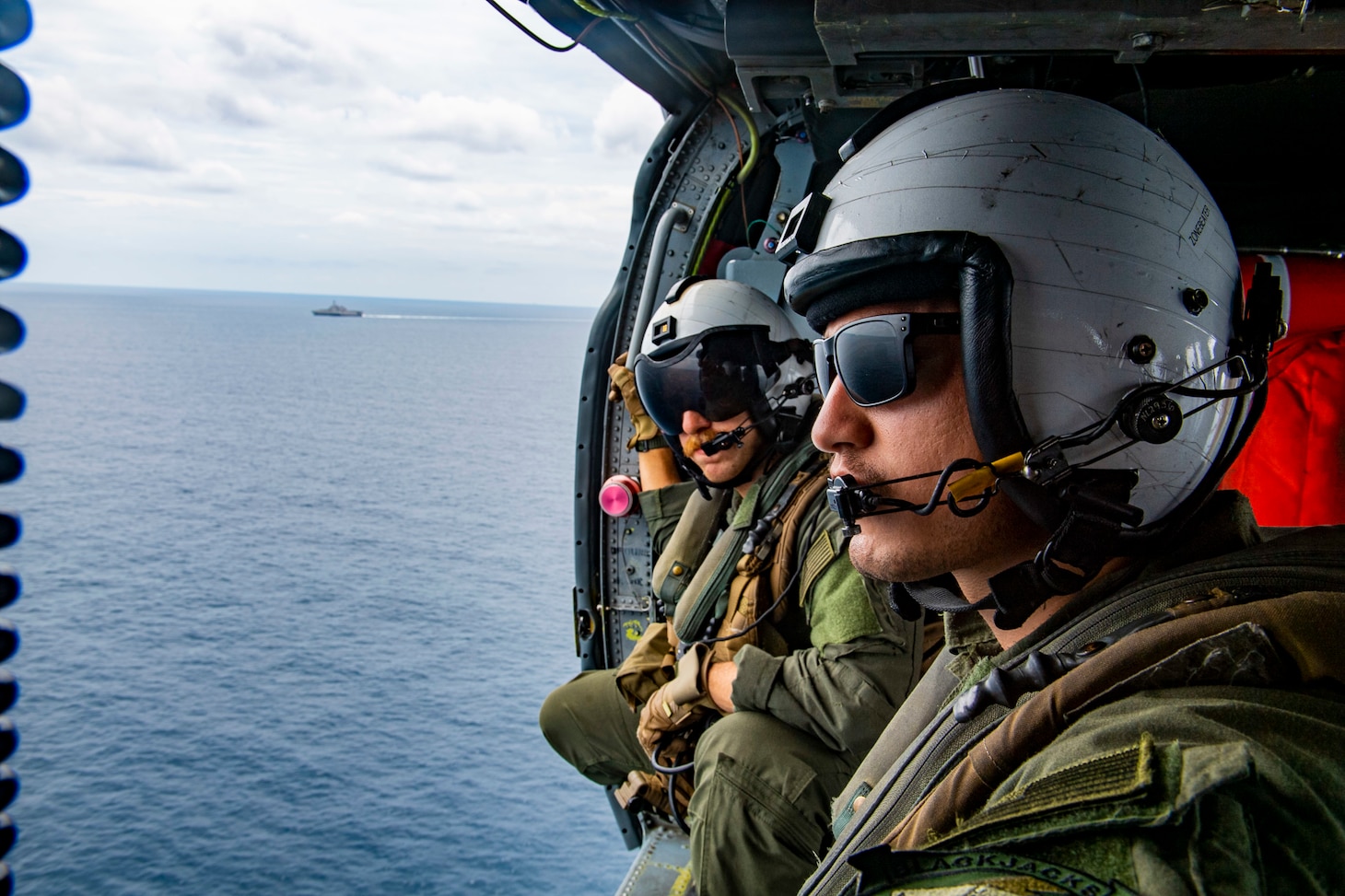 STRAIT OF MALACCA (AUG. 14, 2021) Naval Aircrewman (Helicopter) 2nd Class Nicolas Lopez from Artesia, Calif. and Brandon Matlock from Spokane, Wash., keeps a lookout during flight operations inside of a MH-60S Seahawk helicopter assigned to the “Blackjacks” of Helicopter Sea Combat Squadron (HSC) 21 aboard the Independence-variant littoral combat ship USS Tulsa (LCS 16), Aug. 14, 2021. In its 20th year, SEACAT is a multilateral exercise designed to enhance cooperation among 21 participating Southeast Asian countries and provide mutual support and a common goal to address crises, contingencies, and illegal activities in the maritime domain in support of a free and open Indo-Pacific. (U.S. Navy photo by Mass Communication Specialist 3rd Class Richard Cho)