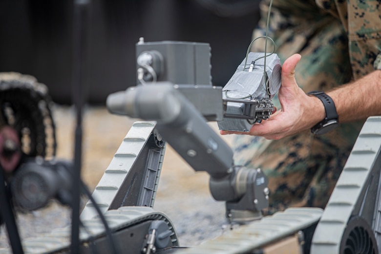 U.S. Marine Corps Sgt. Joshua Upright, an explosive ordnance disposal (EOD) trainee with 3rd Maintenance Battalion, 3rd Marine Logistics Group, applies a drop-charge to an XM1216 Small Unmanned Ground Vehicle during a demolition range on Camp Hansen, Okinawa, Japan, Aug. 18, 2021. EOD technicians conducted a demolition range to increase proficiency in using nonstandard demolition techniques including drop-charge detonations, time-fuse setups and a robotics platform to remotely emplace charges. (U.S. Marine Corps photo by Lance Cpl. Alex Fairchild)