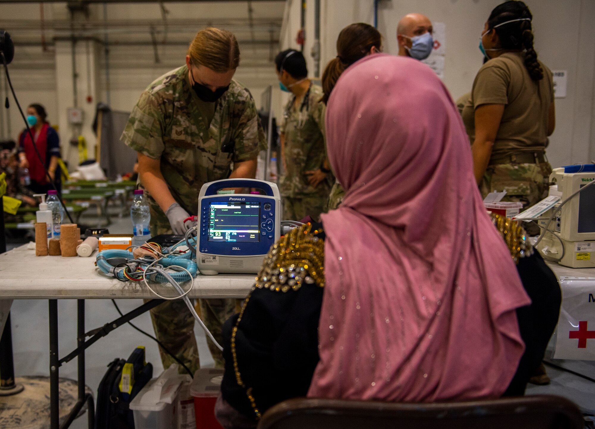 An Airman from the 379th Expeditionary Medical Group provides medical care for Afghanistan evacuees at a hangar, Aug. 19, 2021.