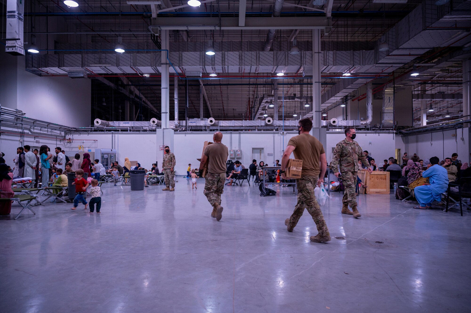 Airmen carry supplies into a building in Southwest Asia where Afghan citizens are added to flight manifests Aug. 19, 2021.