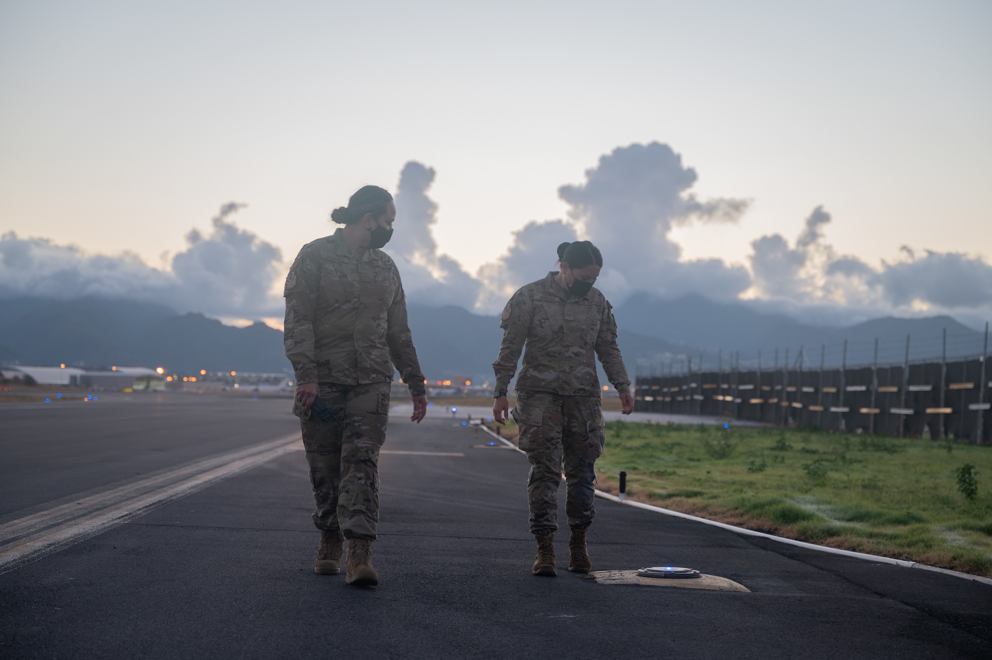 Senior Airmen Moana Melendez and Veronica Mendoza, airfield management specialists with the Hawaii Air National Guard 154th Operations Support Squadron, examine runway lights on their daily inspection before sorties begin for exercise Sentry Aloha at Joint Base Pearl Harbor-Hickam, Hawaii, Aug. 18, 2021. This small group of mission-critical service members helps to ensure the safety and success of HIANG flights out of Hickam Airfield and Daniel K. Inouye International Airport.