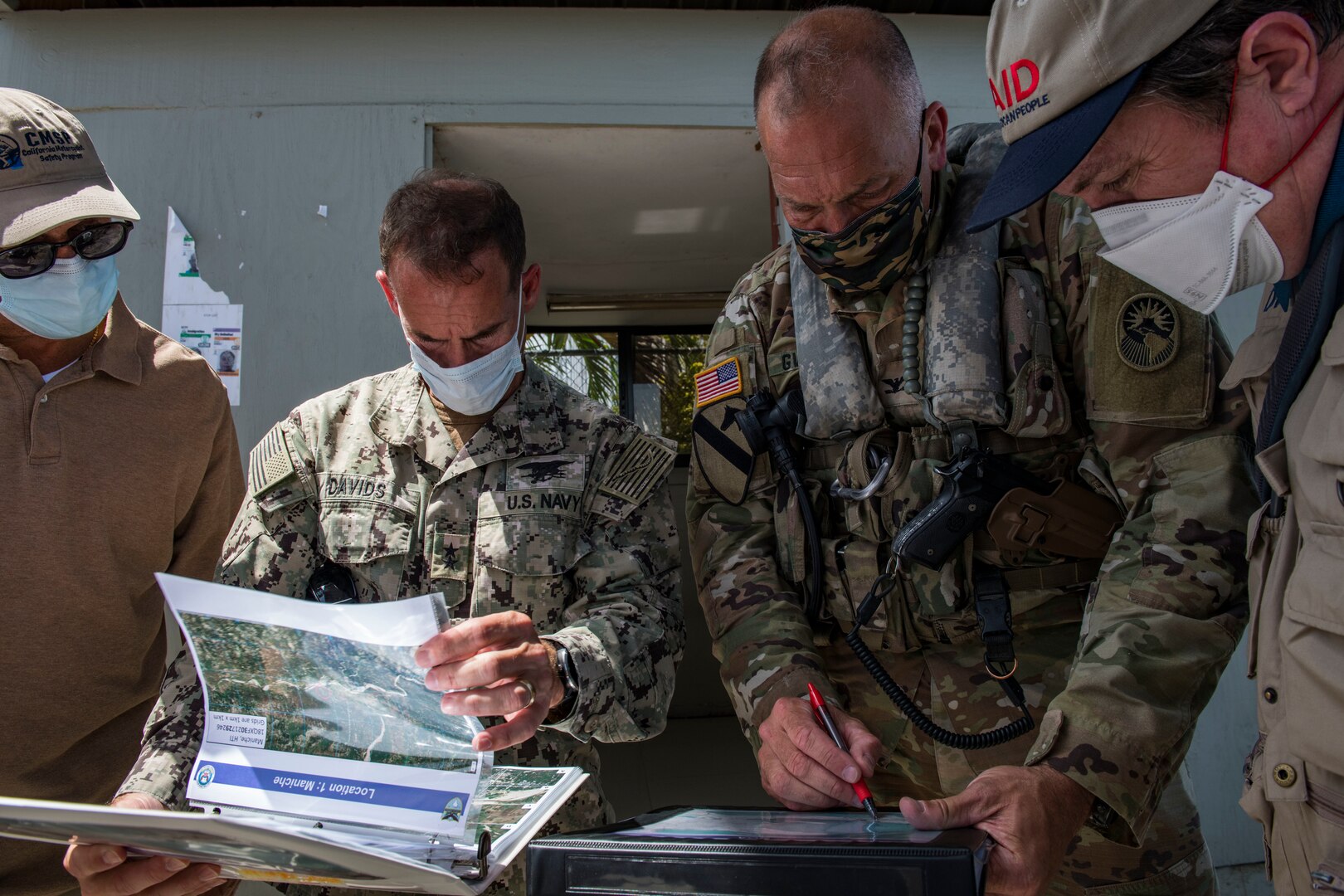 Military leaders look at briefing slides in a folder.