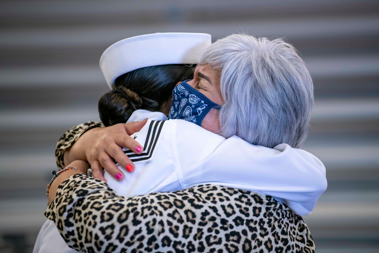 A Sailor embraces with a family member inside Midway Ceremonial Drill Hall after graduating from Recruit Training Command.