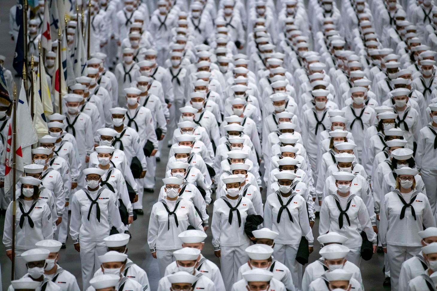 Sailors graduating from boot camp stand in formation after entering Midway Ceremonial Drill Hall during a pass-in-review graduation ceremony at Recruit Training Command.