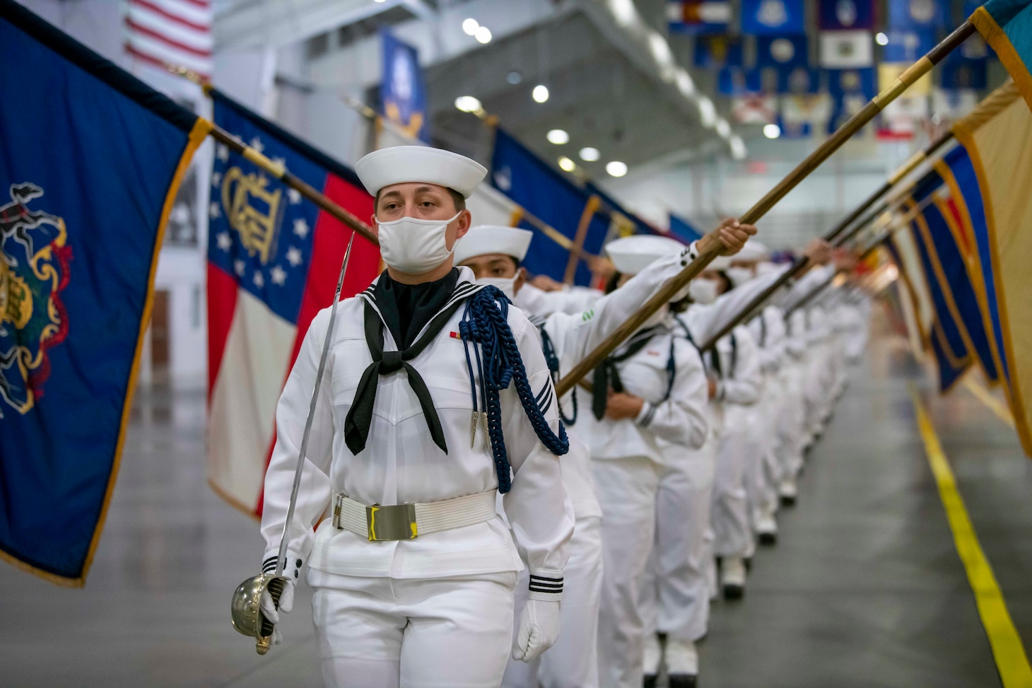 Performance division recruits carrying state flags march on the drill deck.