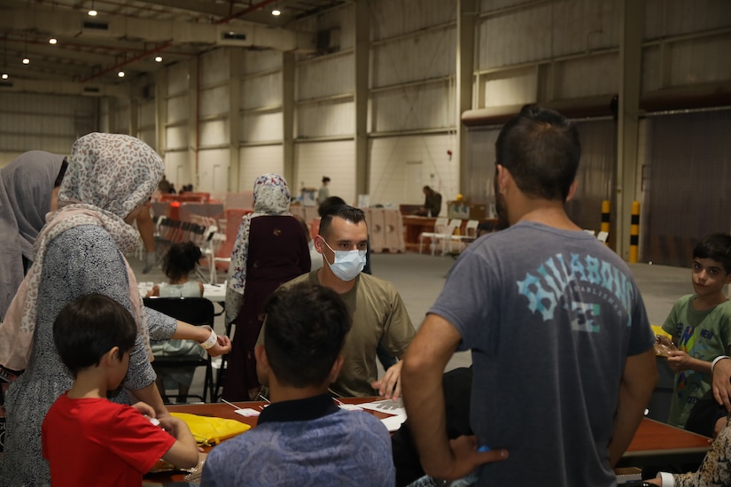 Sgt. Wyatt Ryser, combat medic, 811th Hospital Center, gives a Covid-19 briefing to an Afghan family at Camp As Sayliyah, Qatar, Aug. 20, 2021. Afghan Special Immigrants have the option to receive a Covid-19 vaccination. (U.S. Army photo by Sgt. Jimmie Baker)