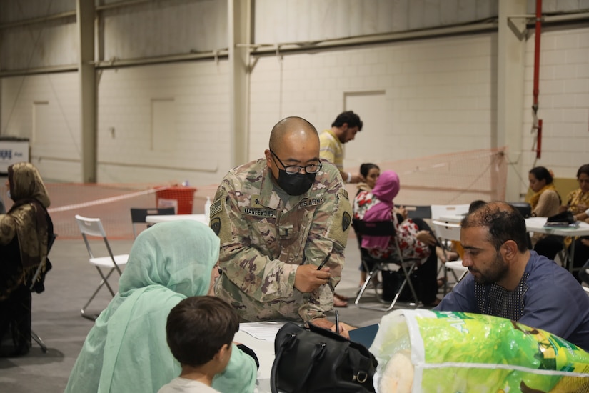 1st Lt. Pisit Manneewony, chaplain, 155th Combat Sustainment Support Battalion, assists an Afghan family during in-processing at Camp As Sayliyah, Qatar, Aug. 20, 2021. Soldiers help process Special Immigration Applicants seeking relocation to the United States.  (U.S. Army photo by Sgt. Jimmie Baker)