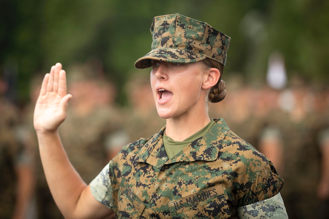 A Marine raises her right hand while talking.