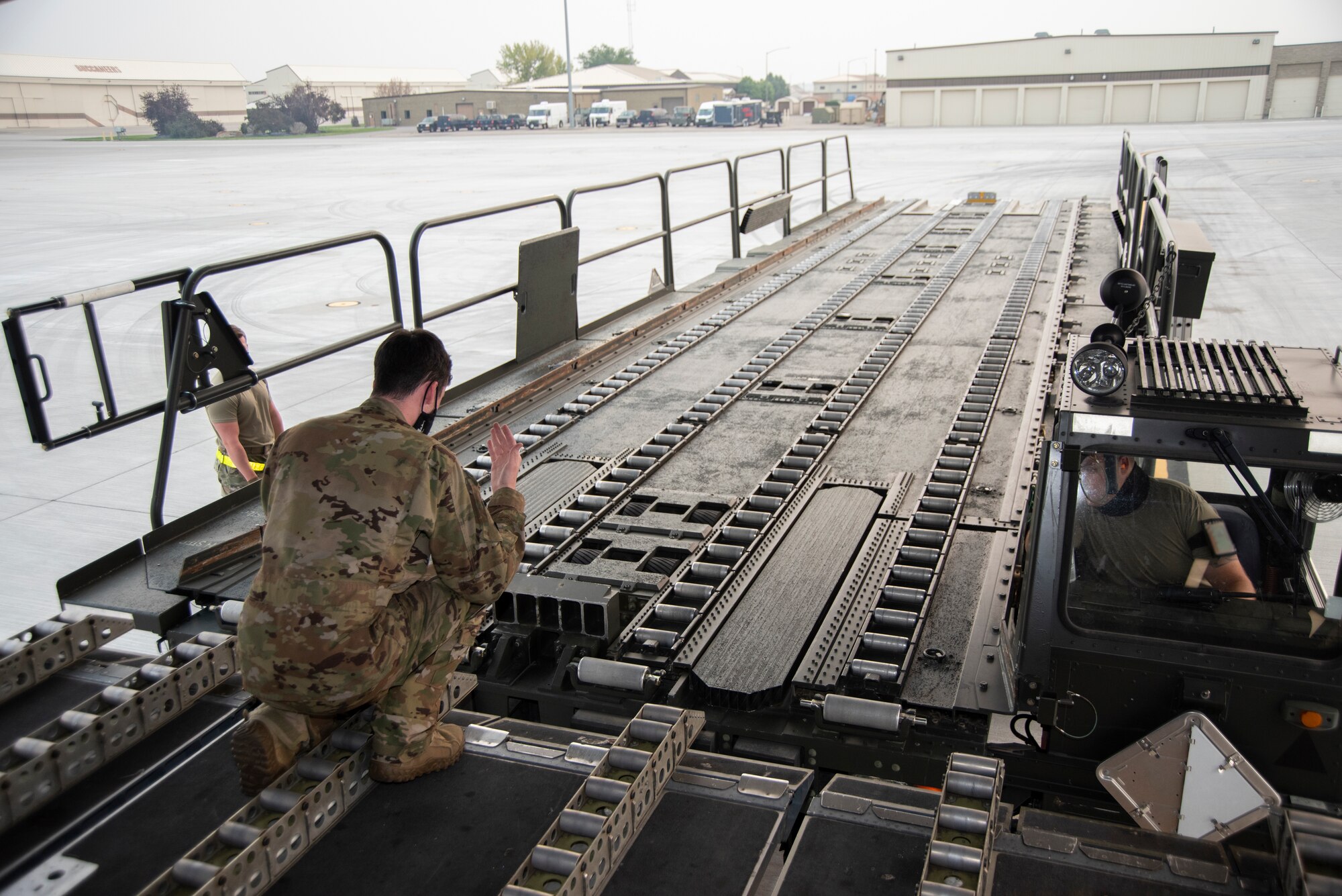 An Airman carefully directs another Airman in parking a 60K Tuner to the rear end of a C-17.