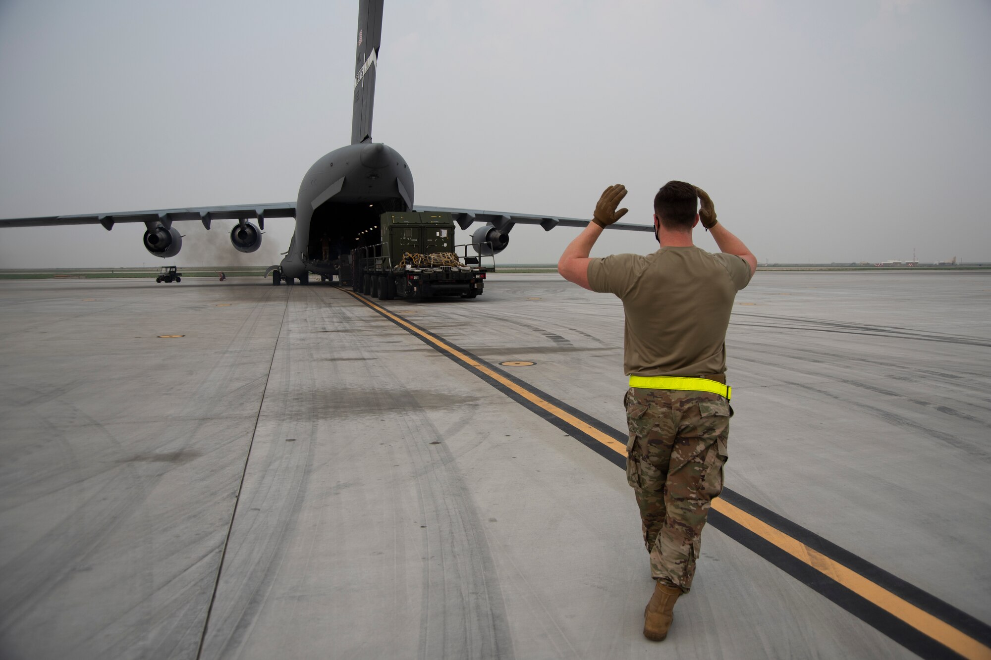 An Airman gives directs to another Airman who is driving in reverse on a 60K Tuner vehicle.