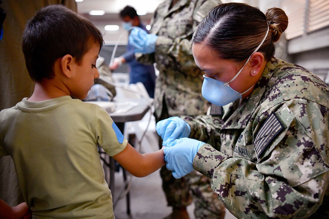 A sailor wearing blue gloves tends to the hand of a child.