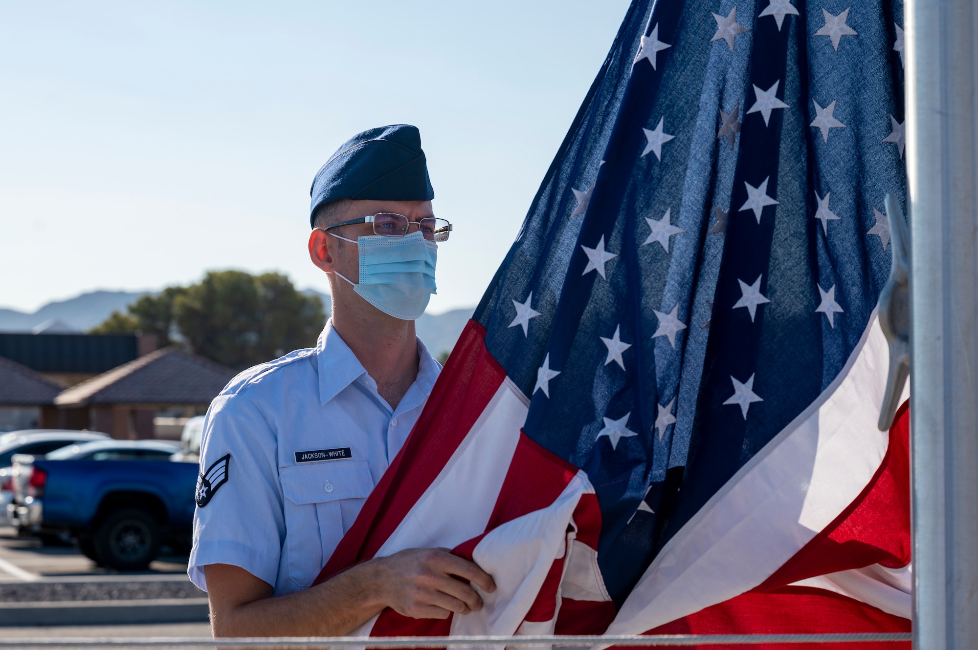 Senior Airman Bryan Jackson-White hangs the American flag during the playing of reveille.