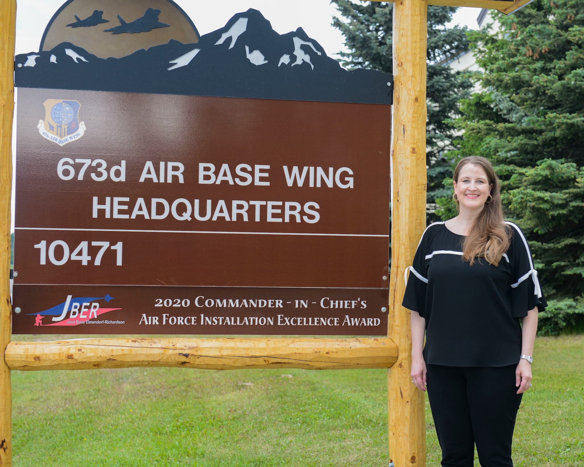 The 673d ABW privatized housing resident advocate poses in front of the 673d ABW Headquarters sign
