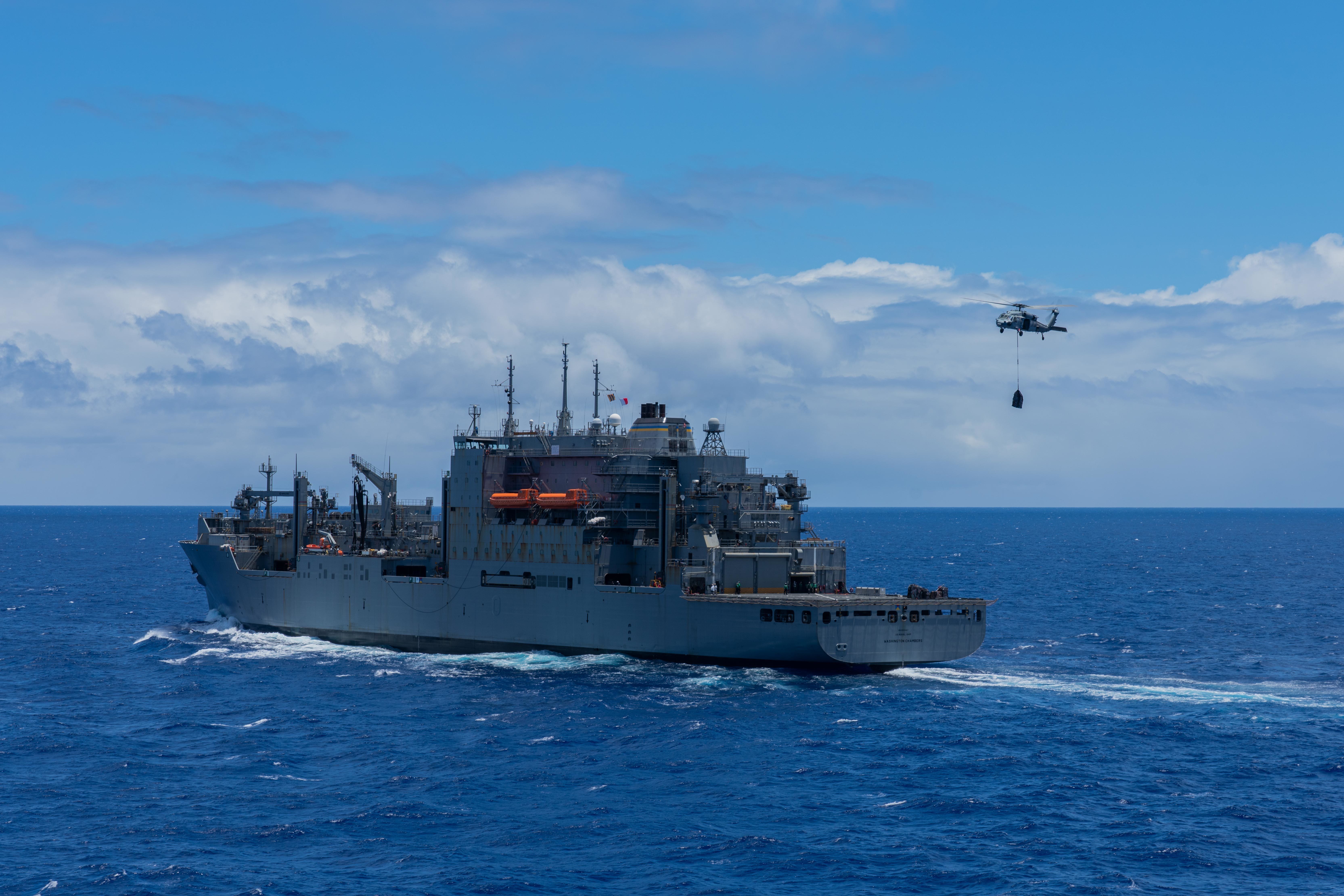 An SH-60 Seahawk, attached to the dry cargo and ammunition ship USNS Washington Chambers (T-AKE 11), lifts off of the flight deck with cargo during a vertical replenishment-at-sea (VERTREP) operation with the amphibious dock landing ship USS Pearl Harbor (LSD 52), Aug 14.