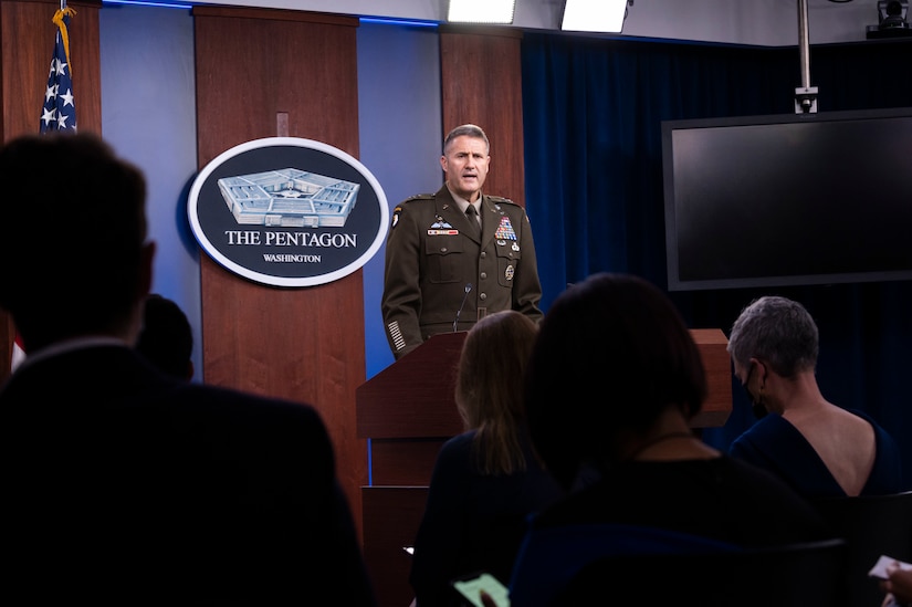 A man dressed in a military uniform faces an audience. The sign in the background indicates that he is at the Pentagon.