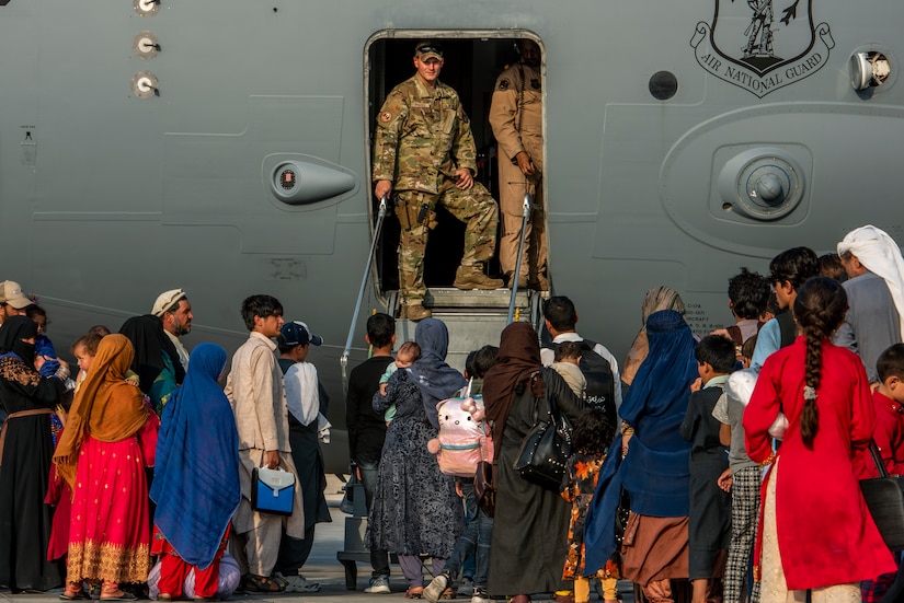 Civilians prepare to board a military aircraft.