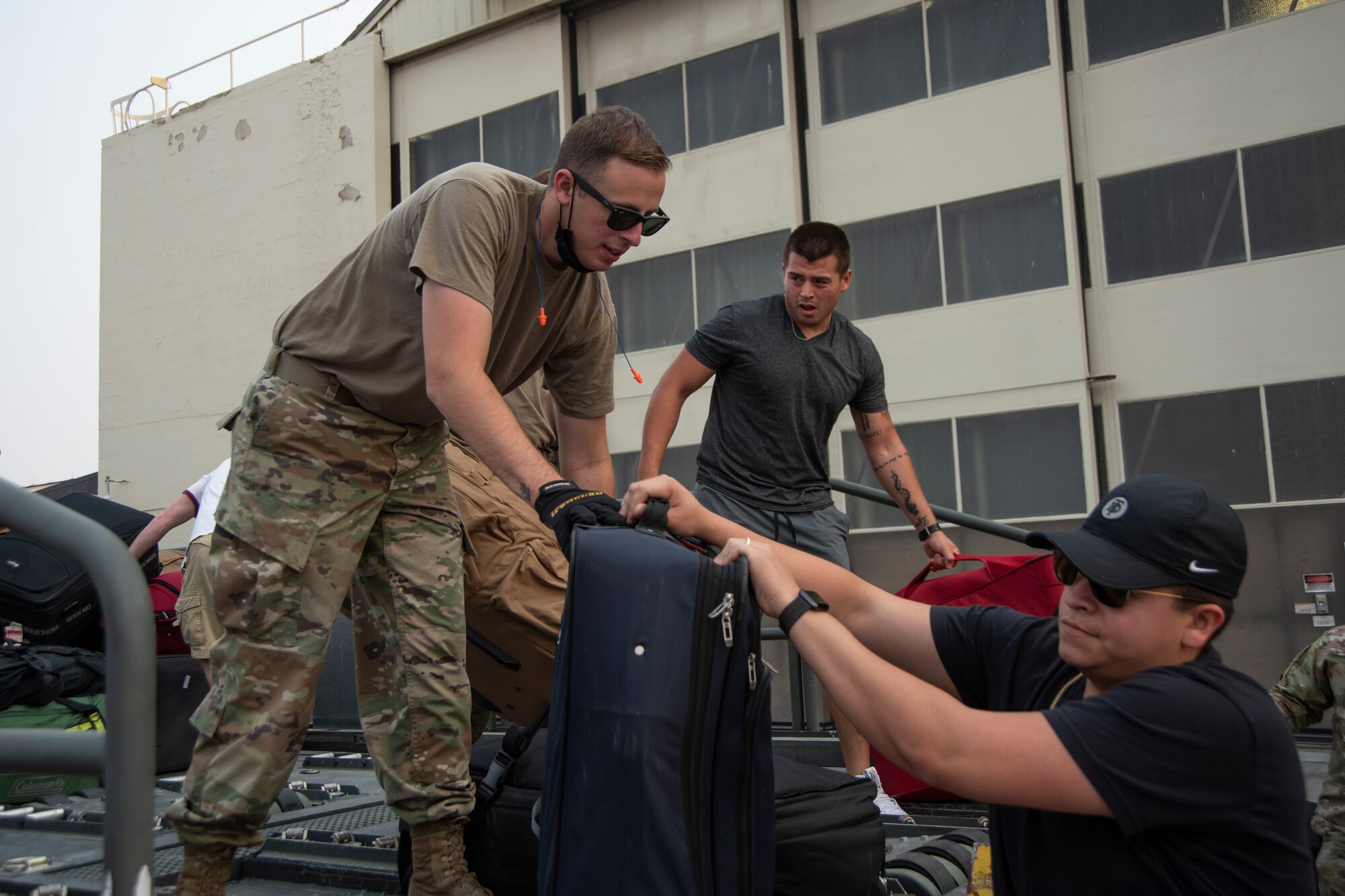 An Airman passes a traveling bag to another Airman in civilian clothing who has returned from deployment.