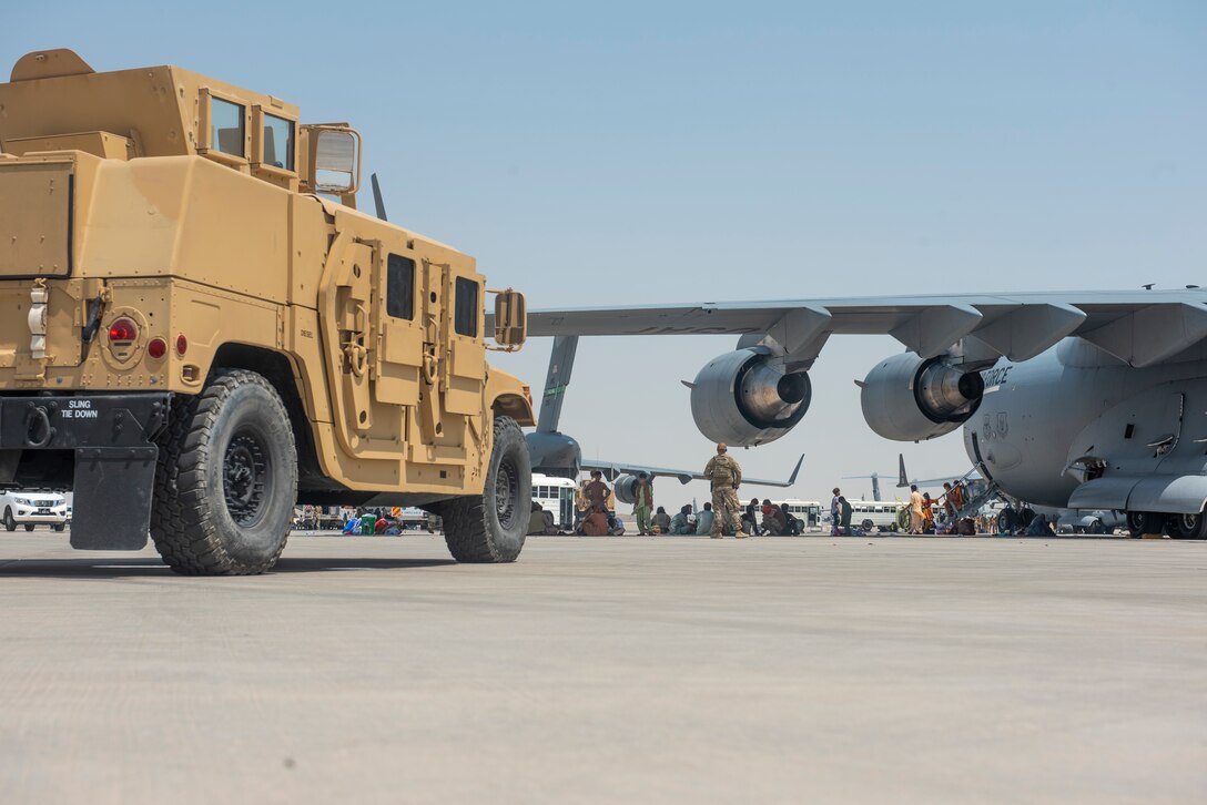 Qualified evacuees wait under the wing of C-17 Globemaster lll after arriving Aug. 20, 2021.