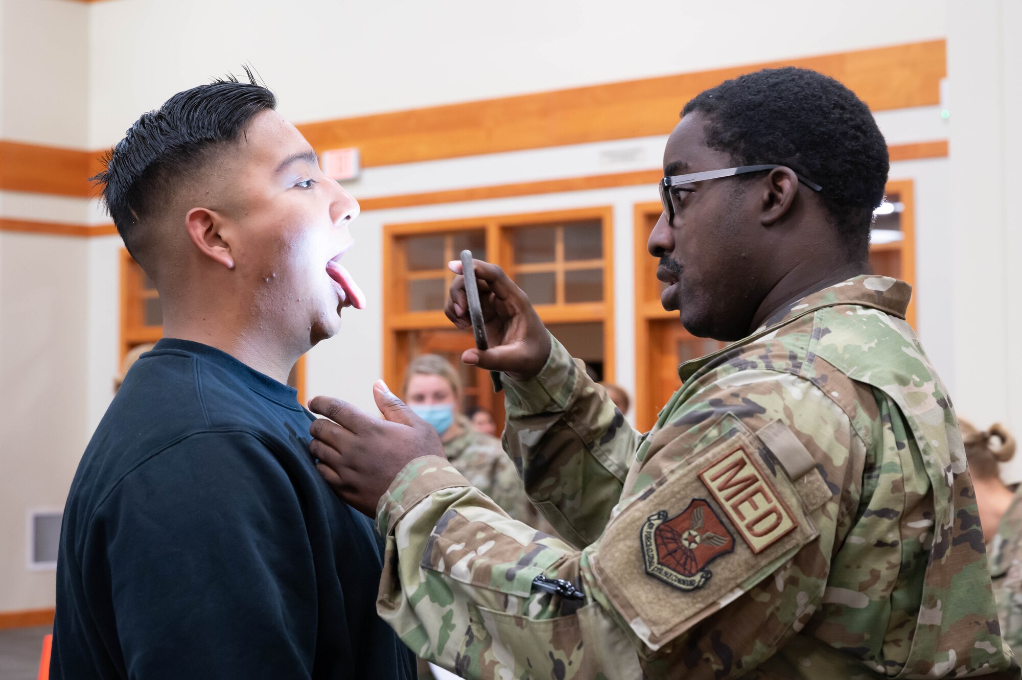 Capt. Bentley Mishael, right, 341st Operational Medical Readiness Squadron physician, uses his phone light to simulate checking the throat of Airman 1st Class Pedro Mendez, 341st Missile Security Forces Squadron defender, Aug. 19, 2021, at Malmstrom Air Force Base, Mont.