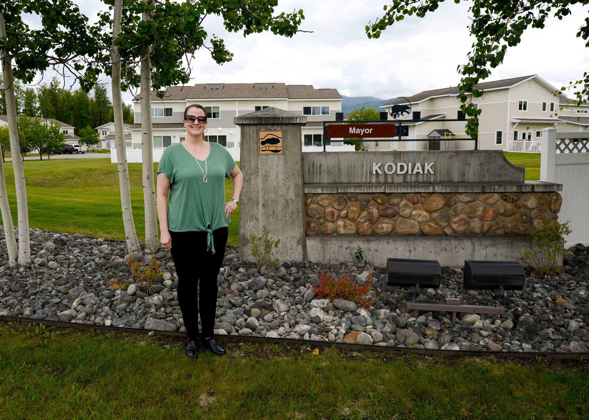The 673d ABW privatized housing resident advocate stands in front of the Kodiak neighborhood sign