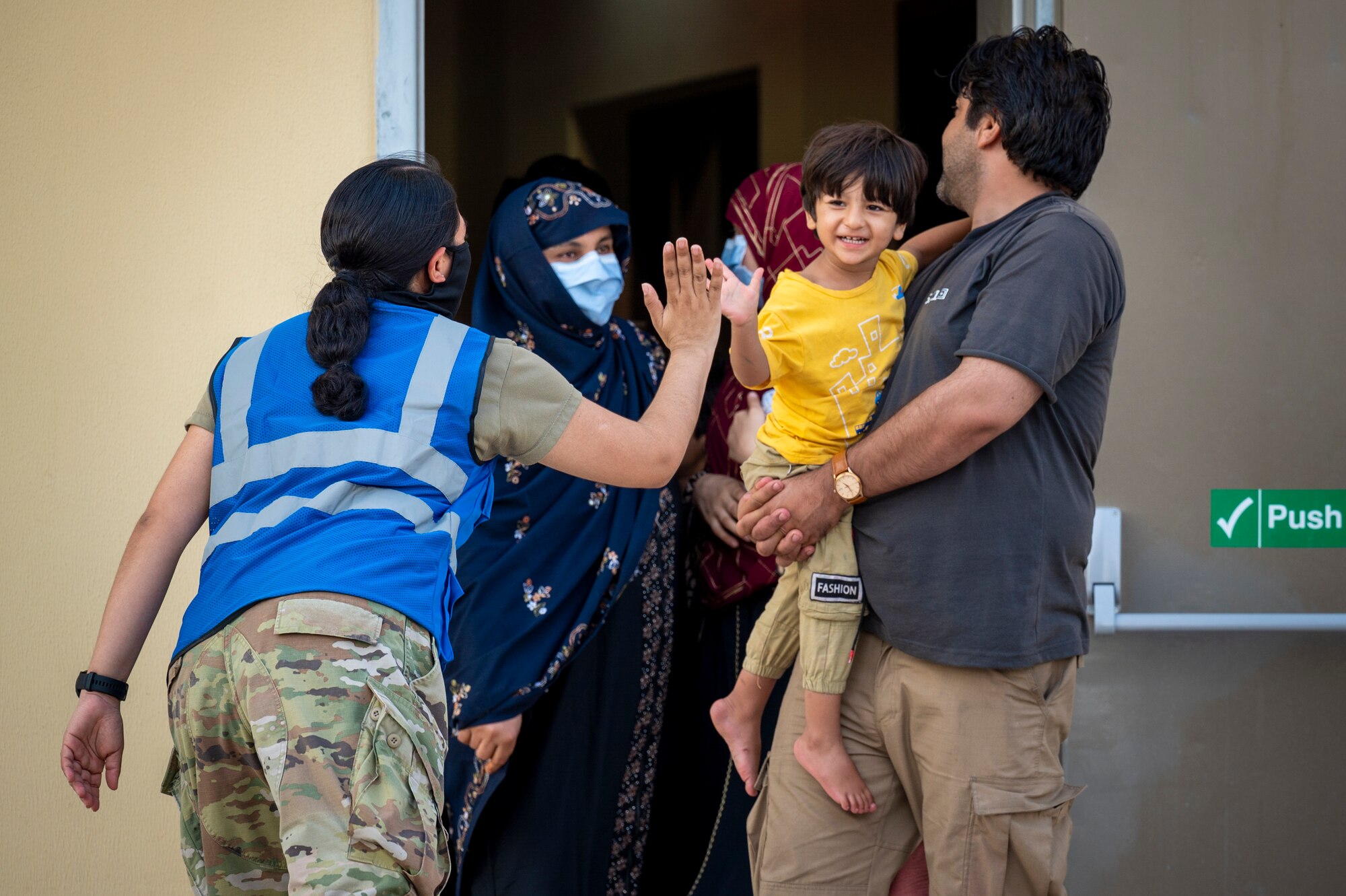 A U.S. service member high-fives a child who was evacuated from Afghanistan Aug. 21, 2021, in an undisclosed location somewhere in Southwest Asia.