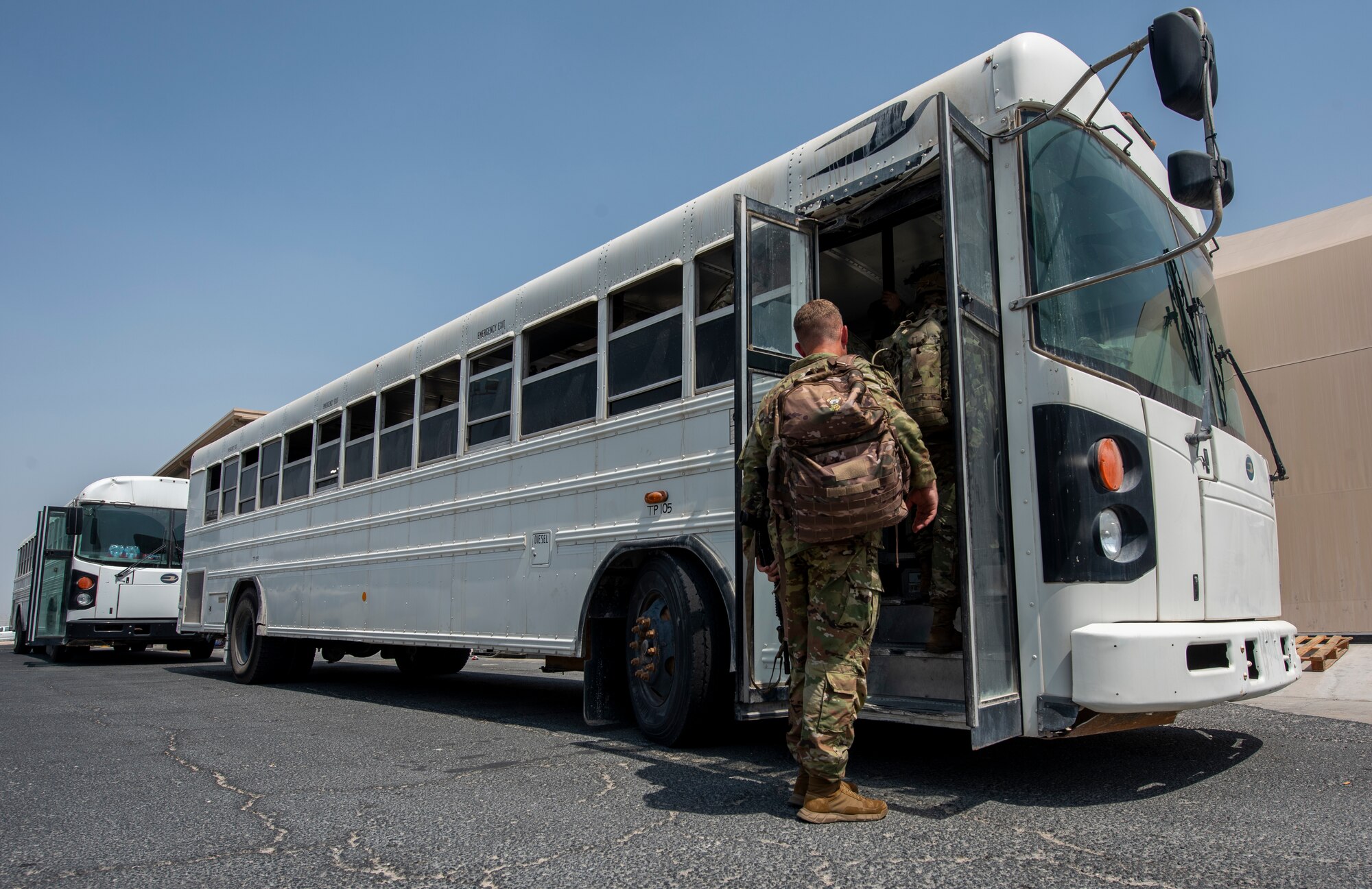Service members board a bus prior to deploying to Afghanistan Aug. 19, 2021, at Al Udeid Air Base, Qatar.