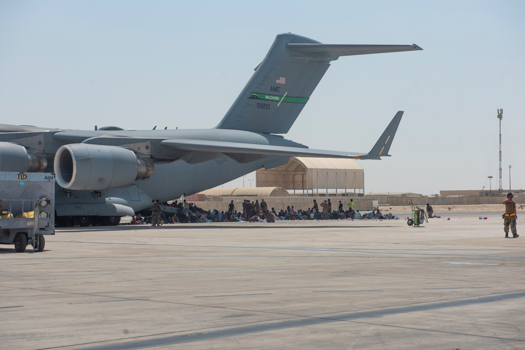 Qualified evacuees wait under the wing of C-17 Globemaster lll before they are able to process onto the aircraft, Aug. 20, 2021.