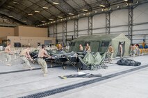 210819-N-IJ992-0183 U.S. 5TH FLEET AREA OF OPERATIONS (Aug. 19, 2021) - U.S. Navy personnel construct a tent in a hanger in the U.S. 5th Fleet area of operations for use during efforts to support the safe transit of U.S. citizens and evacuees from Afghanistan. The U.S. 5th Fleet area of operations encompasses nearly 2.5 million square miles of water area and includes the Arabian Gulf, Gulf of Oman, Red Sea and parts of the Indian Ocean. (U.S. Navy photo by Mass Communication Specialist Seaman Andy A. Anderson)