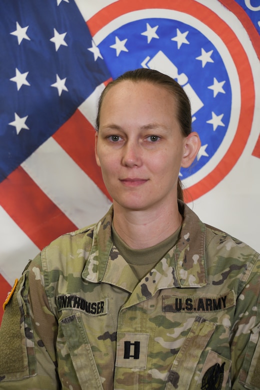 photo of a woman in army uniform standing in front of flags.