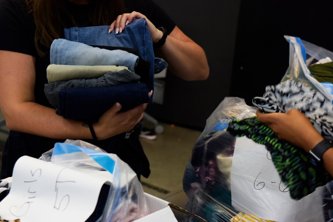 Civilian volunteers sort and fold donated clothing.