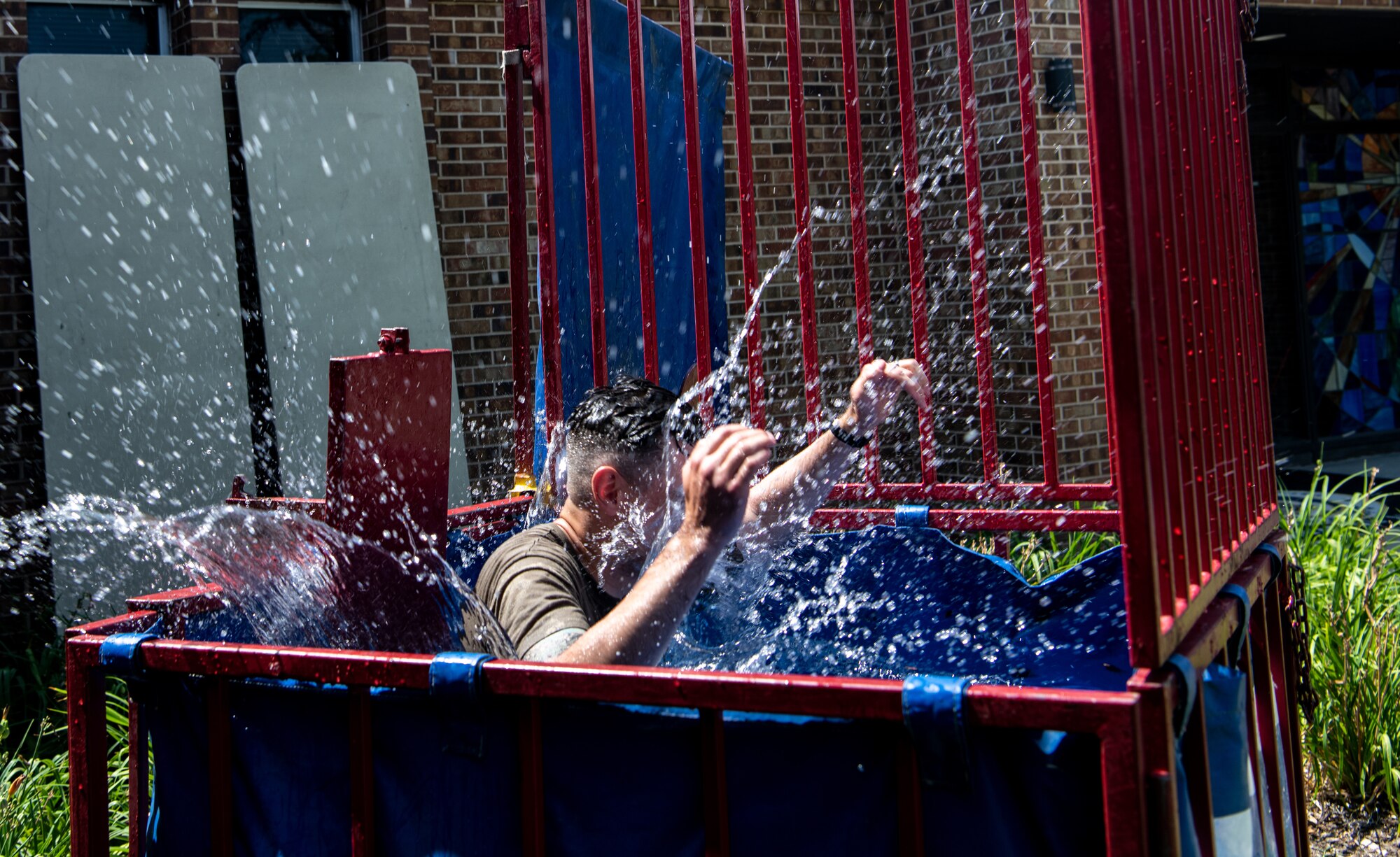 U.S. Air Force Staff Sgt. Travis Leigh, Space Operations Command plans and programs noncommissioned officer in charge, is dunked in a tank during Luau on the Lawn at Peterson Space Force Base, Colorado, Aug. 13, 2021.  The Peterson Chapel Team hosted the resiliency event to get Airmen and Guardians outside together before the summer ends and school begins. (U.S. Space Force photo by Airman 1st Class Joshua Fontenot)