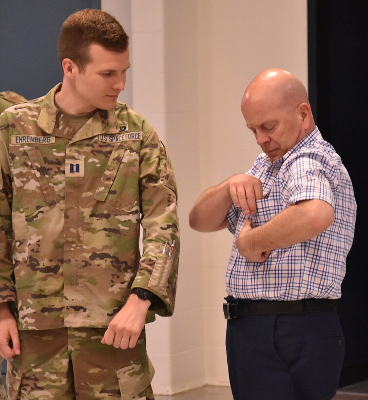 John Florio reaches for Capt. Kenneth Ehrenberg’s new Space Force service patches. (U.S. Air Force photo/Spencer Deer)