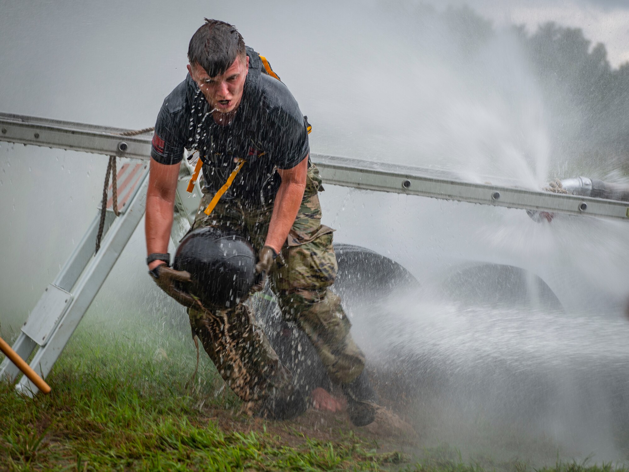 U.S. Air Force Staff Sgt. Chad Jarvis, 103rd Security Forces Squadron, carries a medicine ball through a tunnel while being sprayed with water during the physical training portion of the Connecticut SWAT Challenge in West Hartford, Connecticut, Aug. 19, 2021. The competition brings together tactical operators from across the nation to train SWAT weapons tactics, movements, and physical fitness. (U.S. Air National Guard photo by Tech. Sgt. Steven Tucker)