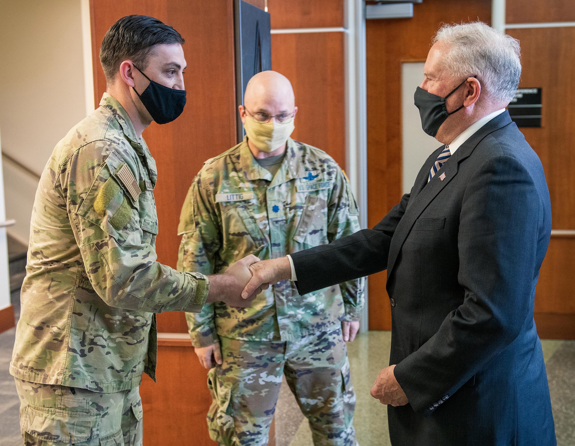 U.S. Air Force Staff Sgt. Trevor Schreckengost (left), the Buckley Garrison NCO in charge of occupational safety, receives a challenge coin from Secretary of the Air Force Frank Kendall, at the Buckley Garrison headquarters building on Buckley Space Force Base, Colo., Aug. 23, 2021.