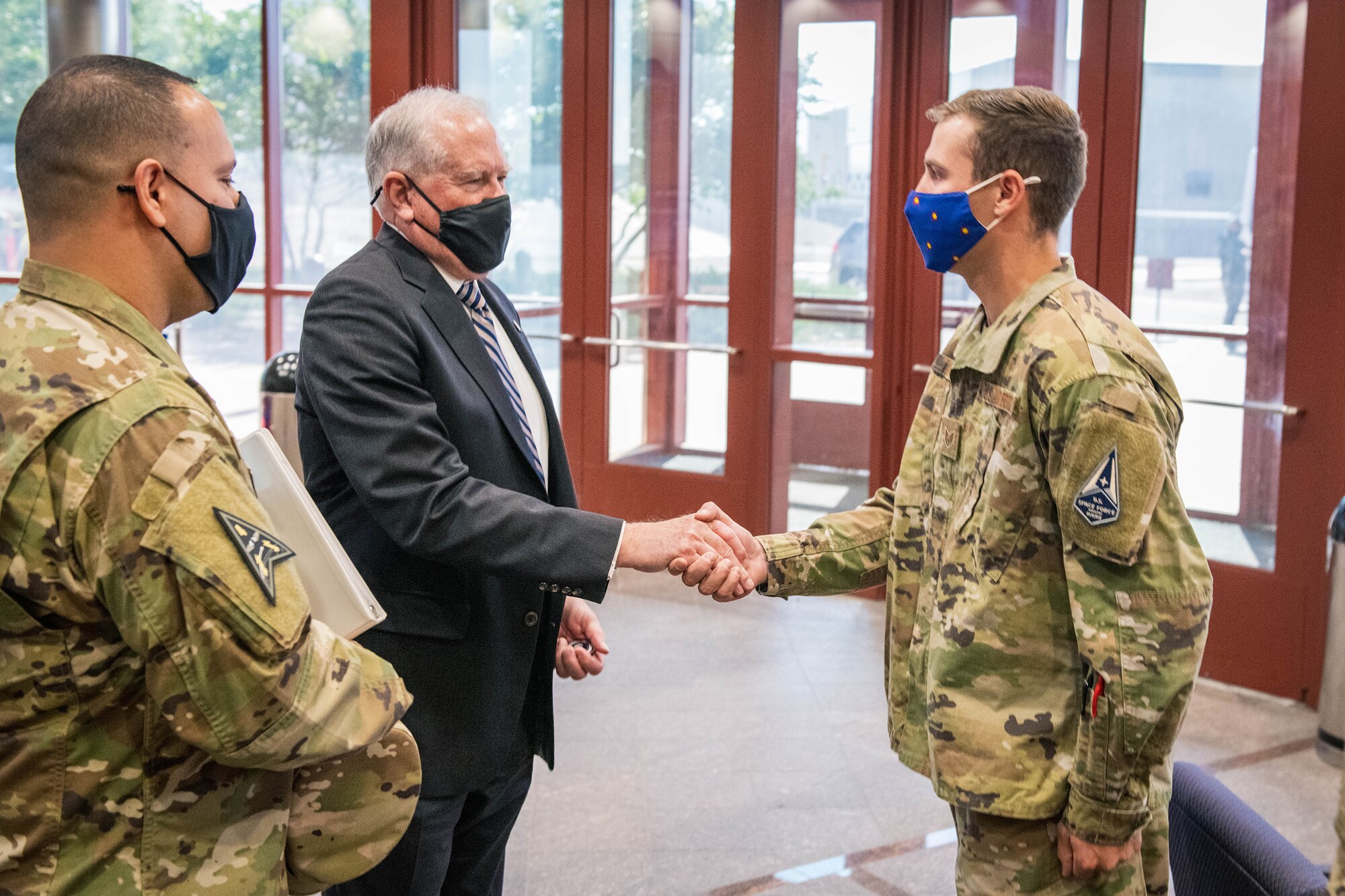 Secretary of the Air Force Frank Kendall gives a challenge coin to U.S. Air Force Staff Sgt. Adam Nevue, a Space Delta 4, Detachment 1 plans and projects NCO, in the Mission Control Station lobby on Buckley Space Force Base, Colo., Aug. 23, 2021.