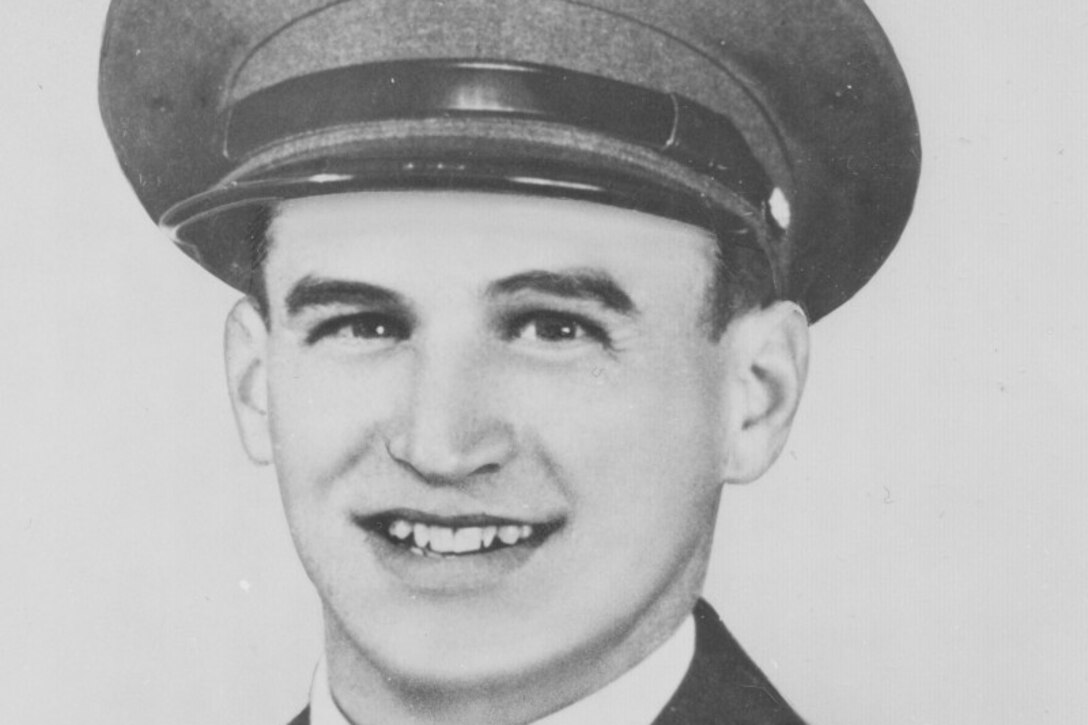 A young man in a military uniform poses for a photo.