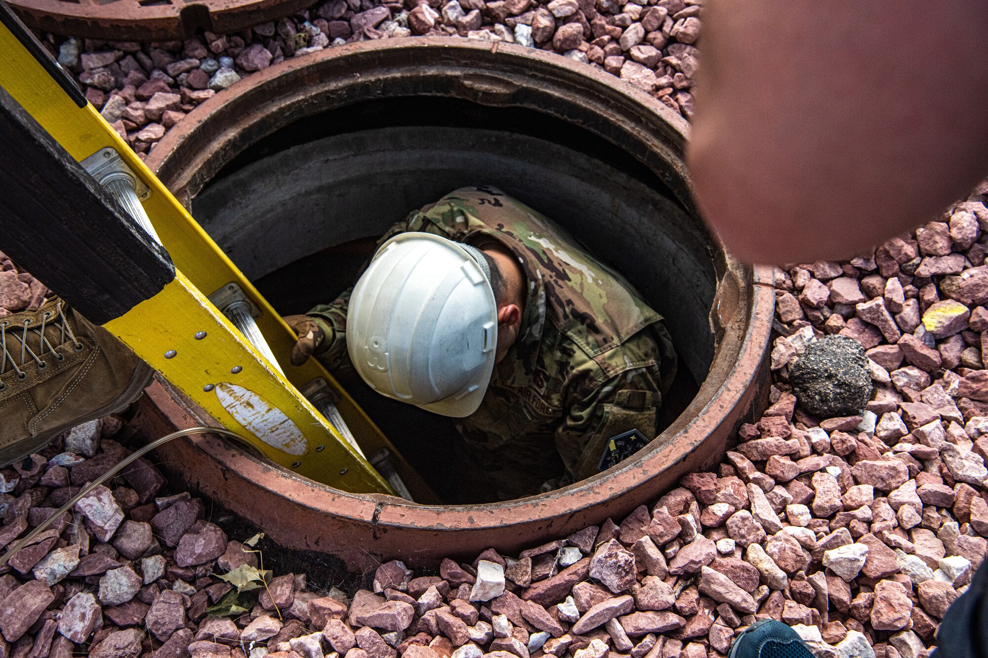 PETERSON SPACE FORCE BASE, Colo. - U.S. Air Force Col. David Wilson, 21st Mission Support Group commander, descends into a maintenance hole during his in-place temporary duty with the 21st Communication Squadron at Peterson Space Force Base, Colorado, Aug. 20, 2021. The squadron uses defense red switch, military strategic and tactical relay, land mobile radio, and network server infrastructure equipment to achieve their mission. (U.S. Space Force photo by Airman 1st Class Joshua Fontenot)
