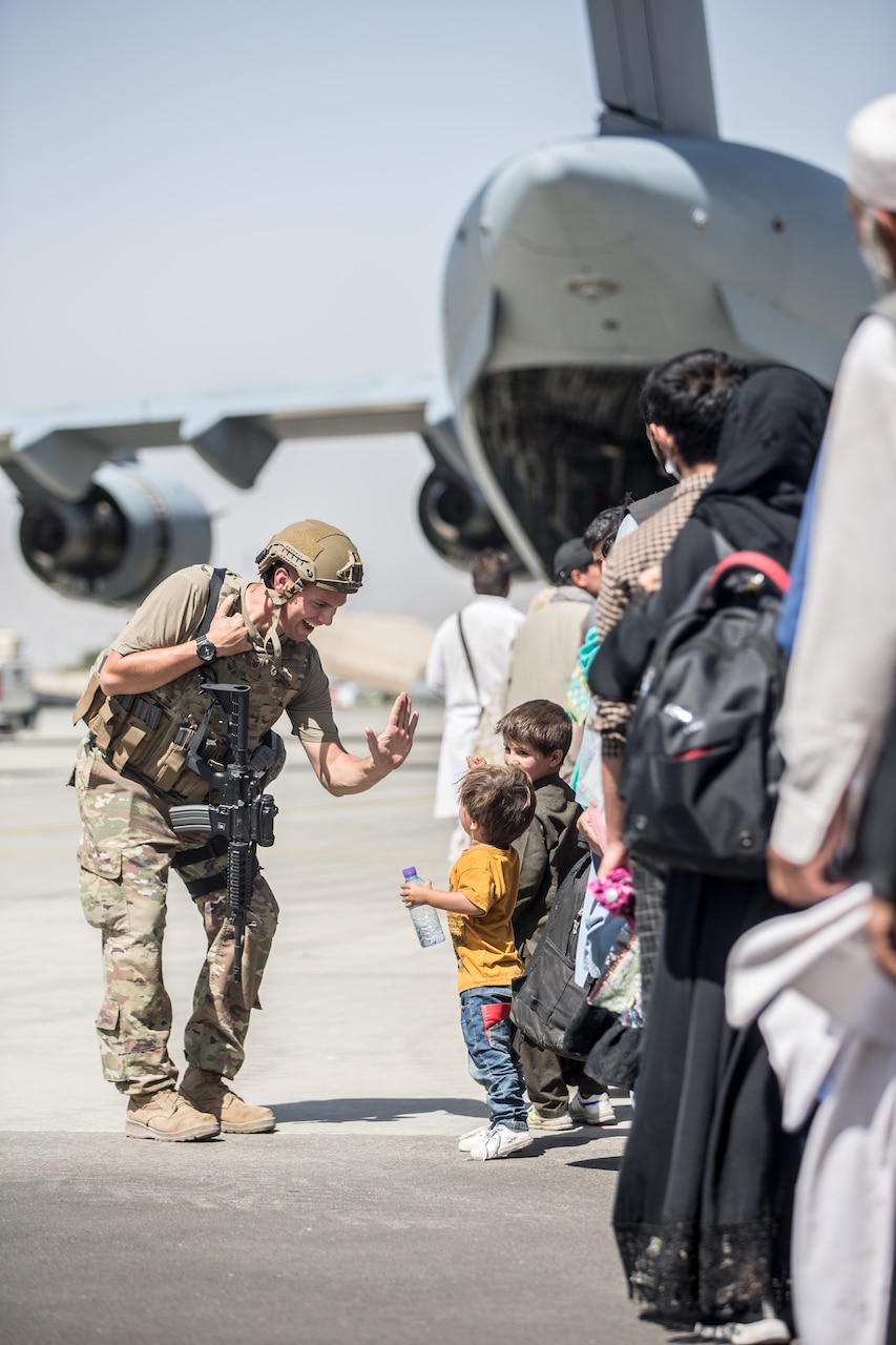 Civilians line up behind a large military aircraft.