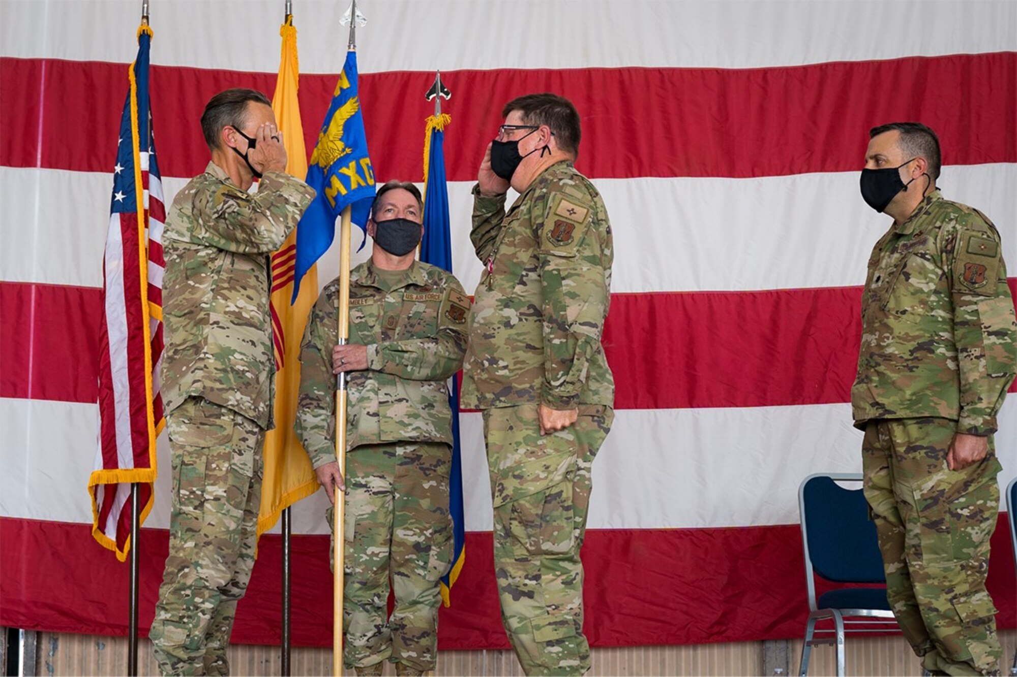 Two colonels salute each other on stage during a ceremony.