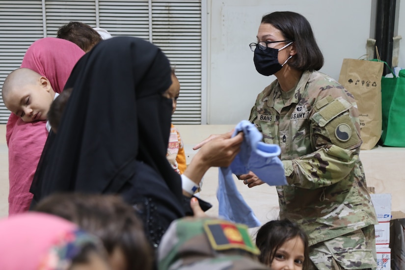 A U.S. Army National Guard Soldier with Task Force Spartan, U.S. Army Central, assists families recently evacuated from Afghanistan as they arrive at Camp Buehring, Kuwait, Aug. 23, 2021. U.S. Army Soldiers continue to work with their U.S. Central Command and Department of State teammates to support Afghanistan evacuation efforts with transportation, security, logistics and medical assistance at locations in Kuwait. (U.S. Army Photo by 1st Lt.  James Mason)