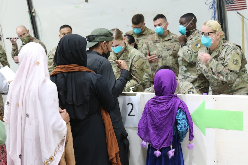 U.S. Army National Guard Soldiers with Task Force Spartan, U.S. Army Central, welcome and offer immediate assistance to Afghan evacuees as they arrive at Camp Buehring, Kuwait, Aug. 23, 2021. U.S. Army Soldiers continue to work with their U.S. Central Command and Department of State teammates to support Afghanistan evacuation efforts with transportation, security, logistics and medical assistance at locations in Kuwait. (U.S. Army Photo by 1st Lt.  James Mason)