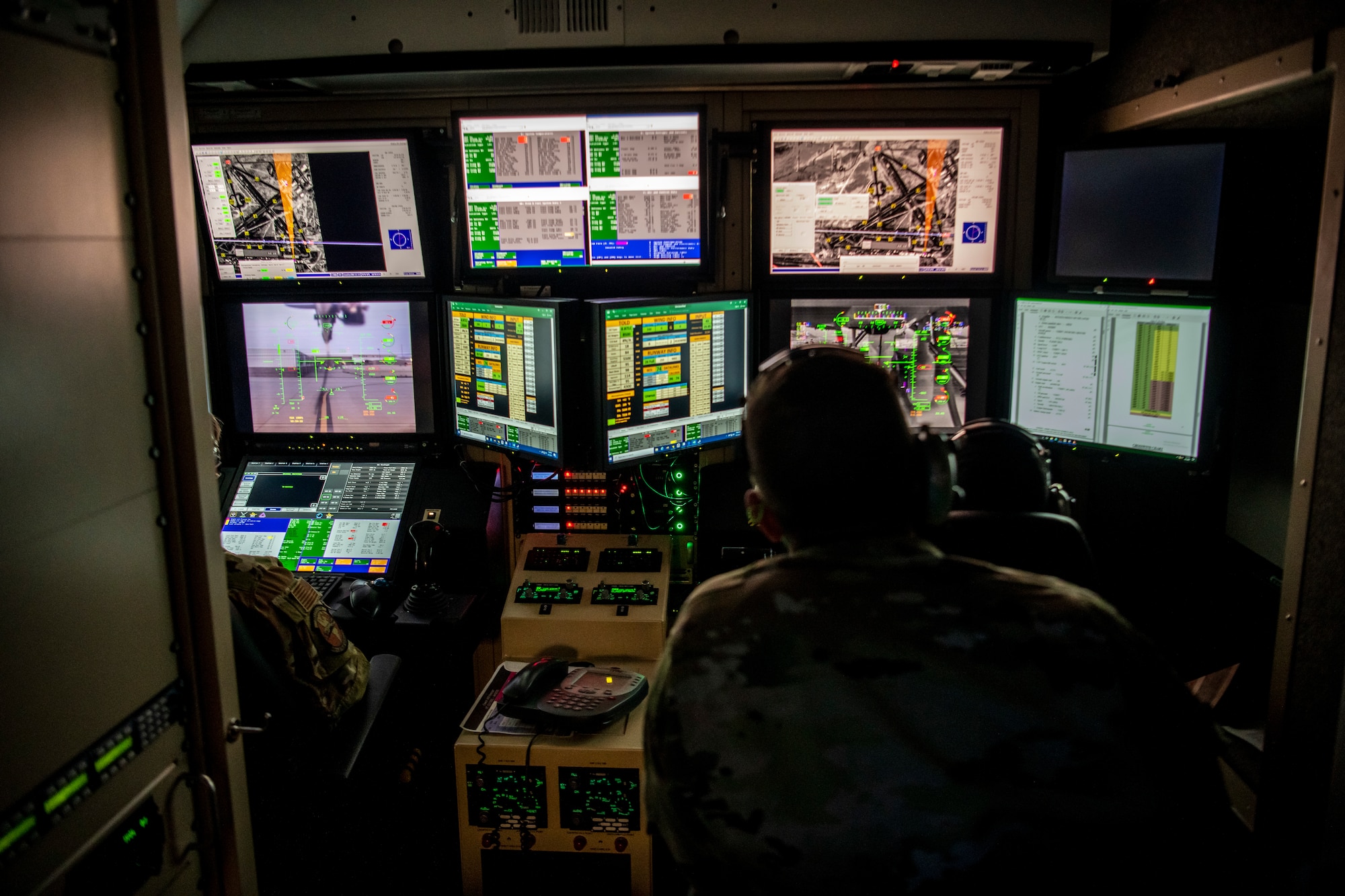 An Airmen watches screens in an enclosed room. Ensuring that the Automated Takeoff and Landing Capability works smoothly.