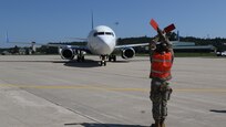 An aircraft transporting vulnerable Afghans is guided at Volk Field on Camp Douglas Wisconsin, Aug. 22, 2021.