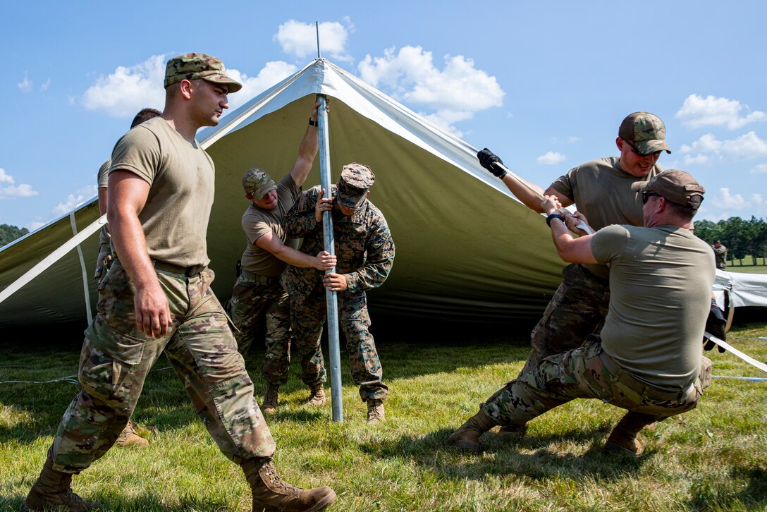 U.S. Marines from Marine Wing Support Squadron 471 and U.S. Air National Guard Airmen from the Volk Field Combat Readiness Training Center (CRTC) work together to raise reception tents for the arrival of Afghans at Volk Field Air National Guard Base, Wisconsin, Aug. 19, 2021.