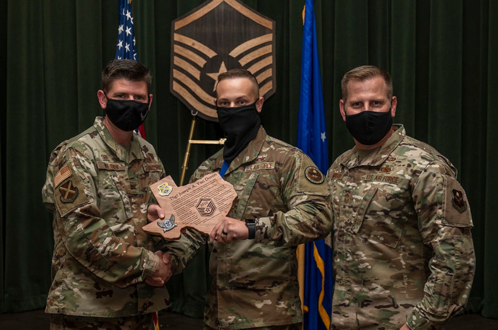 3 military members in front of a master sergeant plaque