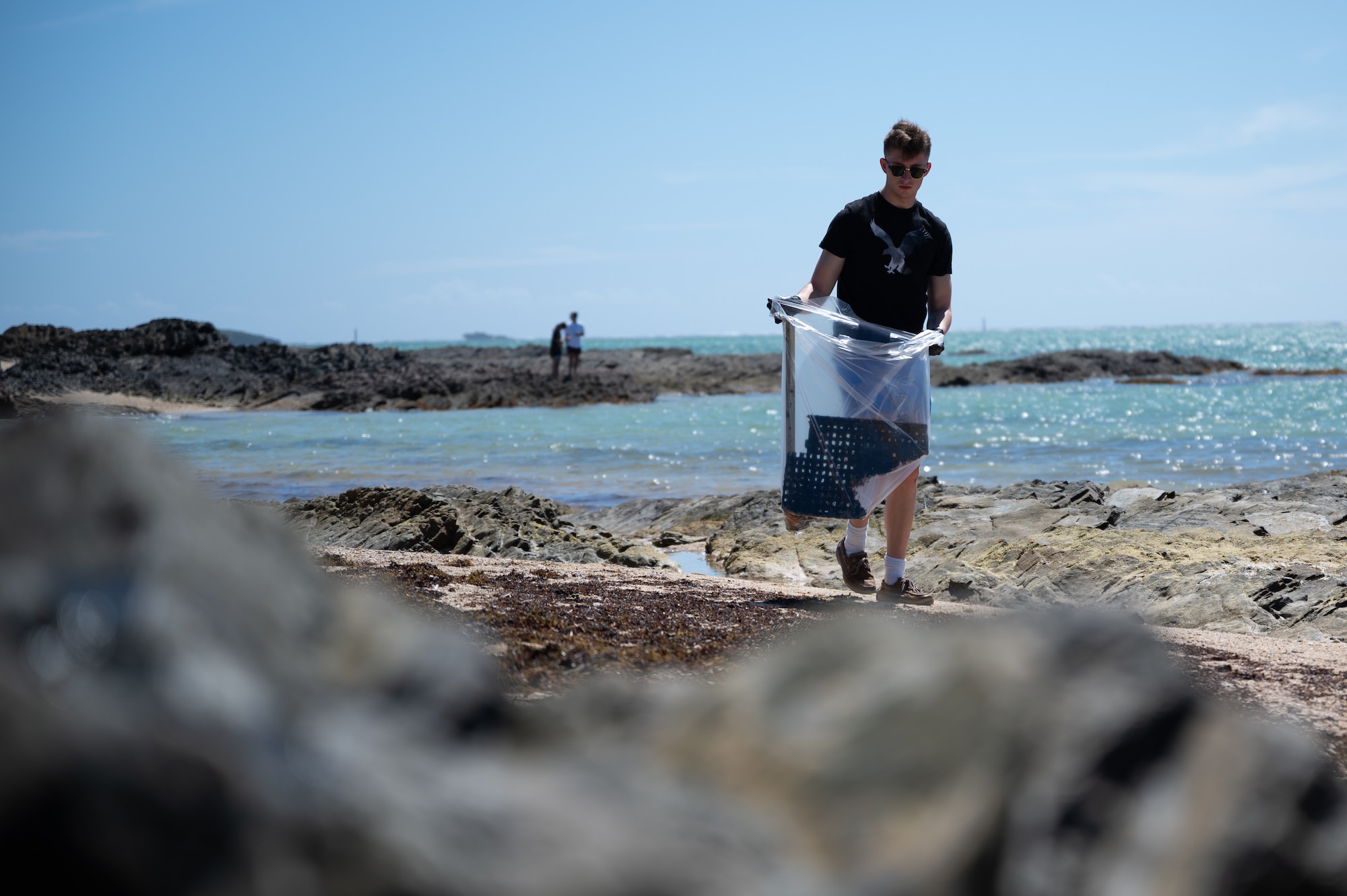 U.S. Air Force Airman Gavin Mattingly, 718th Force Support Squadron force management technician, picks up garbage at Seaglass Beach on Okinawa, Japan, Aug. 21, 2021. Globally, over 300-thousand volunteers come out to help clean up beaches annually; this beach clean-up removed over one hundred pounds of trash from the beach. (U.S. Air Force photo by Airman 1st Class Stephen Pulter)